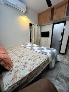 a small bedroom with a bed with a flowered blanket at Mayura home in Pondicherry