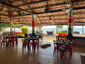 a restaurant with tables and chairs and a dog laying on the floor at Tribal Huts Community in Daanbantayan