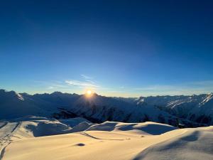 a sun setting over a snow covered mountain range at Pension Lenz in Ischgl