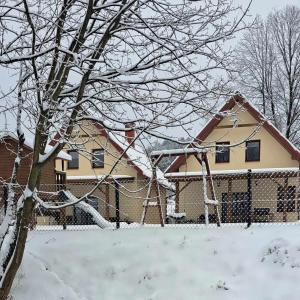 uma casa coberta de neve com um baloiço em Słoneczna Sielanka domki w Bieszczadach em Ustrzyki Dolne