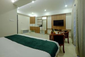 Dormitorio con cama, escritorio y TV en The HEARTLAND Hotel en Thiruvananthapuram