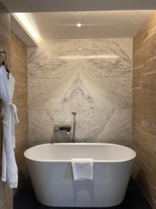 a bath tub in a bathroom with a marble wall at Hotel Barahi Kathmandu in Kathmandu