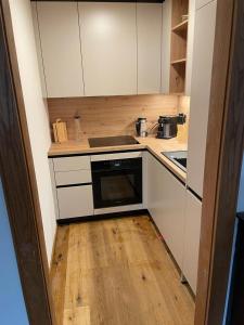 eine kleine Küche mit weißen Schränken und Holzböden in der Unterkunft Best place Apartment "Ambiente" include Jokercard in Saalbach-Hinterglemm