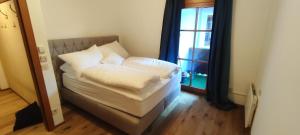 Bett mit weißer Bettwäsche und Kissen in einem Zimmer mit Fenster in der Unterkunft Best place Apartment "Ambiente" include Jokercard in Saalbach-Hinterglemm
