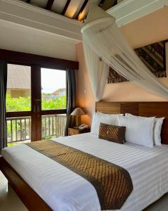 a bedroom with a large bed with a window at Villa Puriartha Ubud - CHSE Certified in Ubud