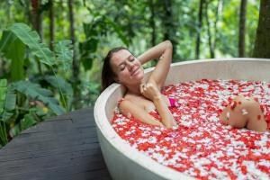 una donna sdraiata in una vasca da bagno piena di peperoni rossi di Amarta Pesagi Retreat Tabanan a Tabanan