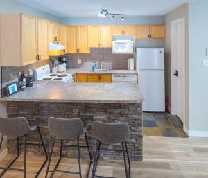 a kitchen with a large counter with three stools at 2 Bedroom and Wall Bed Mountain Getaway Ski In Ski Out Condo with Hot Pools Sleeps 8 in Panorama