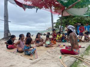 a group of children sitting on the beach at Tribal Huts Community in Daanbantayan