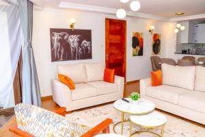 ein Wohnzimmer mit weißen Möbeln und orangefarbenen Kissen in der Unterkunft Sangara by Edmor Suites in Nairobi