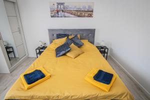 1 cama amarilla grande con 2 almohadas azules. en Ramūs apartamentai, en Anykščiai
