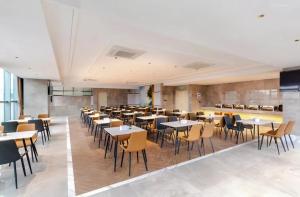 un restaurante con mesas y sillas en una habitación en Vienna International Hotel Shenzhen Baolong subway Station branch, en Longgang