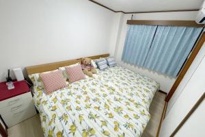 un cane seduto su un letto in una camera da letto di Rainbow House ad Osaka