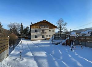 una casa con parque infantil en la nieve en Apartmány U Rodinky, en Lipová-lázně