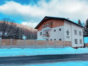 um edifício com uma cerca de madeira na neve em Apartmány U Rodinky em Lipova Lazne