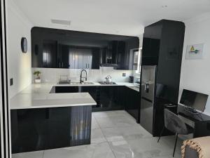 a kitchen with black and white cabinets and a sink at Nicky's Guest House in Roodepoort