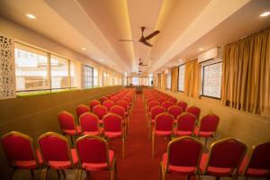 an empty room with red chairs and a ceiling at Oak Field Inn in Cochin