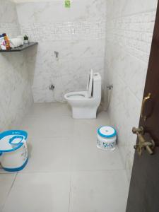 a bathroom with a toilet in a white room at Shiva INN in Varanasi