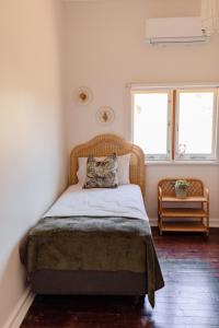 1 dormitorio con 1 cama con cabecero de ratán y 2 ventanas en Pet Friendly Family Home in Bluff Point en Geraldton