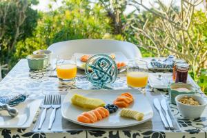stół z talerzami jedzenia i szklanki soku pomarańczowego w obiekcie Days At Sea Beach Lodge w mieście Trafalgar
