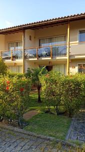um edifício com uma varanda com arbustos em frente em Apartamento condomínio Vila la Torre em Porto Seguro