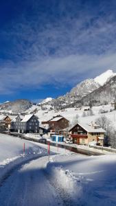 a snow covered town with houses and mountains at Ferienwohnung Haus am Bach in Toggenburg in Wildhaus