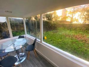 a room with a glass table and chairs and a window at Gravesend 2 Bedroom Spacious Stylish Apartment - Sleeps upto 6 - 2 Min Walk to Station in Kent