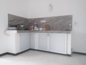 une cuisine avec des placards blancs et un comptoir dans l'établissement Friendly house, à Galle