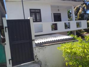 an open door to a white house with a fence at Friendly house in Galle