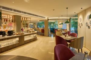 a restaurant with tables and chairs and a bar at Flora Airport Hotel and Convention Centre Kochi in Nedumbassery