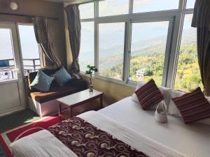 um quarto de hotel com uma cama e uma grande janela em Hotel High Ground Inn Sarangkot em Pokhara