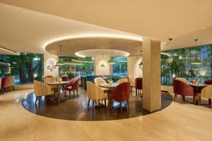 a restaurant with tables and chairs and windows at Flora Airport Hotel and Convention Centre Kochi in Nedumbassery