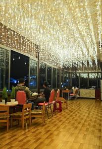 two people sitting at tables in a restaurant with lights at Mai DiaMond Hotel in Da Lat