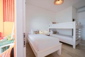 a white bedroom with a bunk bed and a staircase at The Room Padang-Padang in Uluwatu