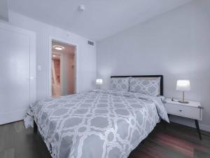 a white bedroom with a large bed and a nightstand at 1BDR&Bath&Den I AC I 600sq.ft I Free WiFi&Parking in Richmond