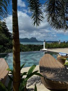 a resort with a pool with chairs and a palm tree at Ahana Resort El Nido in El Nido