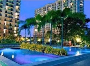 a swimming pool with palm trees in front of a building at Fully Furnished Condo with Balcony Fiber Wi-Fi in Lo-oc