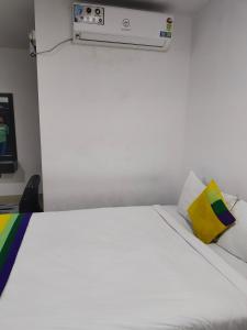 a bedroom with a white bed with a yellow pillow at HOTEL AMIGOS in Hyderabad