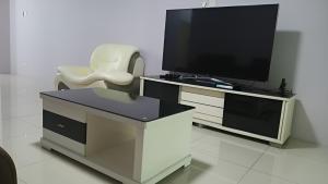 a entertainment center with a flat screen tv and a chair at Daxxlence Swimming Pool Homestay Kinta RiverFront in Ipoh