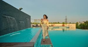 a woman in a dress standing next to a swimming pool at Flora Airport Hotel and Convention Centre Kochi in Nedumbassery