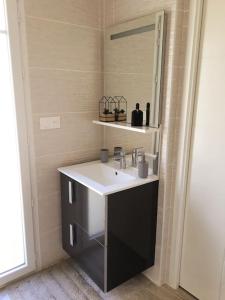 een badkamer met een wastafel en een spiegel bij La Cigale du Pyla, au cœur de l'écoquartier avec piscine commune in La Teste-de-Buch