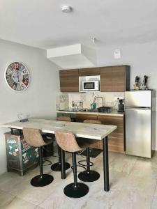 een keuken met een tafel met stoelen en een koelkast bij La Cigale du Pyla, au cœur de l'écoquartier avec piscine commune in La Teste-de-Buch