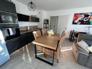 a kitchen and living room with a wooden table and chairs at Charmant T3 proche plaine de l’Ain in Saint-Jean-de Niost
