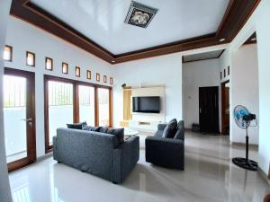 sala de estar con 2 sofás y TV de pantalla plana en Homestay Jogja Prambanan By Simply Homy, en Sleman