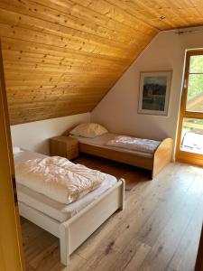 two beds in a room with a wooden ceiling at Das gelbe Landhaus in Tellig