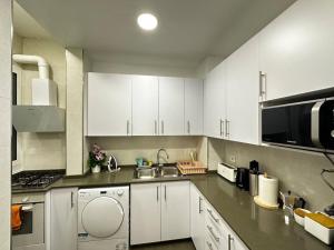 a kitchen with white cabinets and a sink and a microwave at Rooms Nuevo Roger in Barcelona