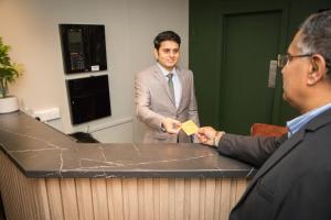 a man is handing another man a card at a counter at Park Inn by Radisson Bournemouth in Bournemouth