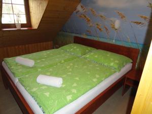 a bed in a room with green sheets and pillows at Penzion Žumberk in Nové Hrady