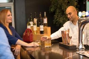a man and a woman sitting at a bar with wine bottles at Park Inn by Radisson Bournemouth in Bournemouth