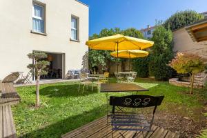 une table avec un parasol jaune, une table et des chaises dans l'établissement MAISON EOLE, à Villeurbanne