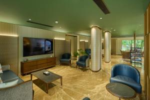 a lobby with chairs and a flat screen tv at Flora Airport Hotel and Convention Centre Kochi in Nedumbassery